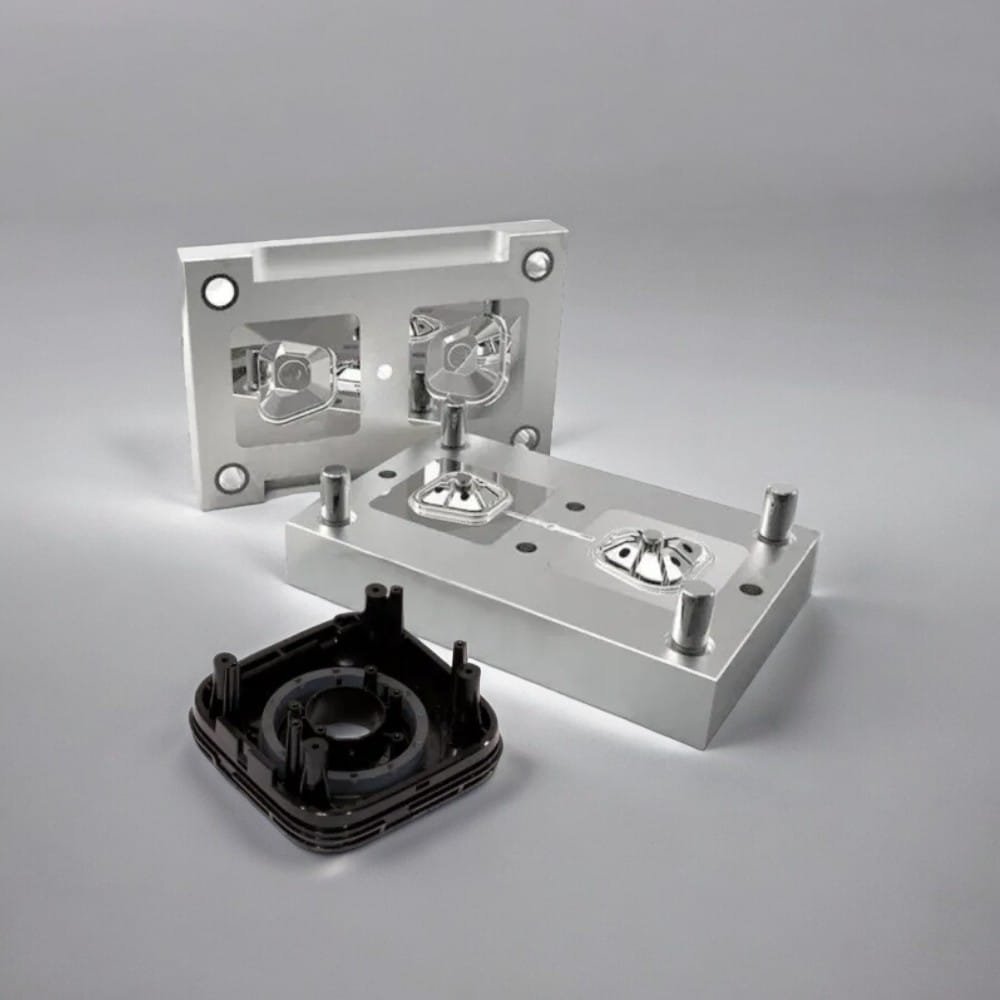 An aluminium injection mould, open to show both halves and the cavities, with the moulded plastic housing it produces