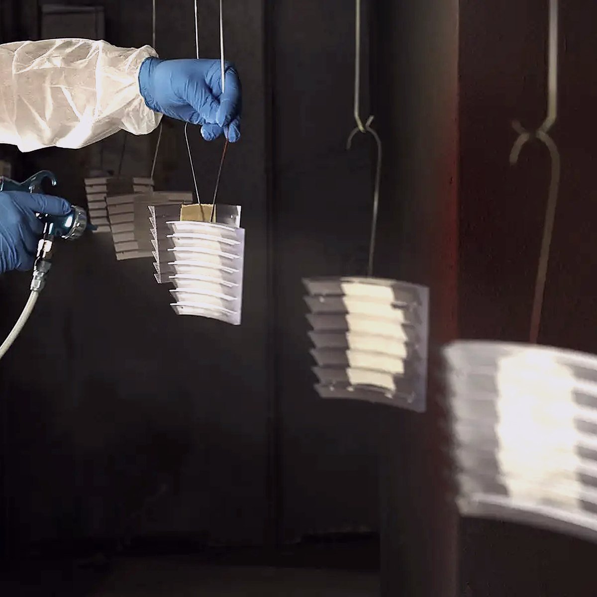 Spraying primer onto printed parts hanging in the finishing booth