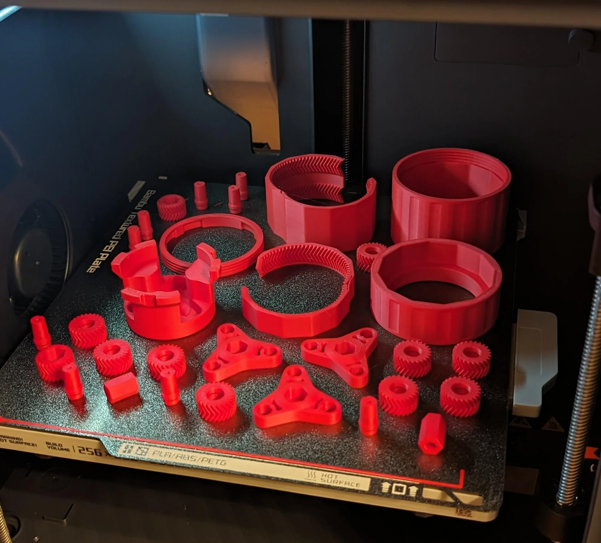Bambu P1S FDM printer with red parts on build plate